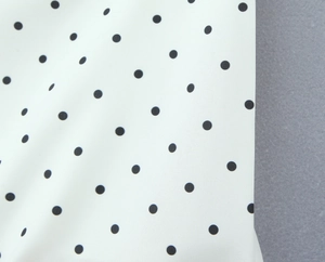 Macro detail of high-quality white fabric with precise black polka dot print pattern