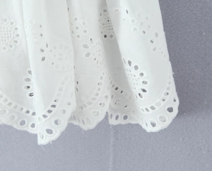 Macro shot of white Broderie Anglaise cotton fabric with intricate floral embroidery detail