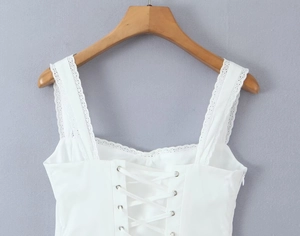 Close-up of white lace trim with corset-style lace-up back and silver eyelets detail