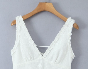 Close-up of white lace dress featuring deep V-neck with delicate floral hollow patterns
