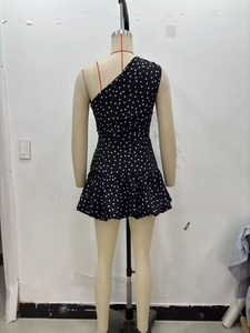 Back view of a one-shoulder black polka dot dress with ruffle hem on a mannequin