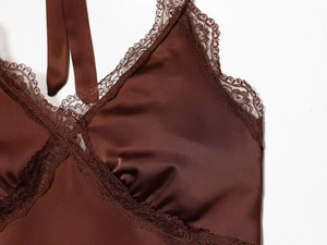 Detail of chocolate brown satin camisole featuring delicate lace trim and halter neck design