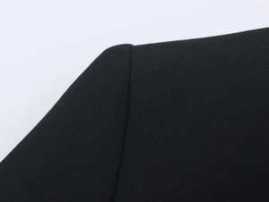 Gros plan sur la couture d'épaule et le tissu texturé d'un blazer noir cintré