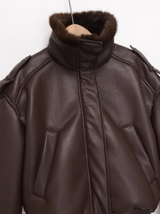 Detail of dark brown faux leather jacket featuring premium faux fur collar and ribbed hem