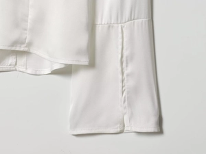 Detailed close-up of white satin shirt cuffs with slit design and smooth fabric texture