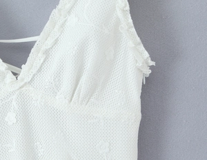 Detailed view of white floral lace fabric with delicate ruffled straps and hidden side zipper