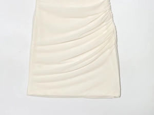 Detail view of cream white ruched mini skirt with elegant draped fabric and sleek texture