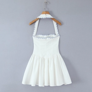 Close-up of white halter dress featuring blue scalloped embroidery and back zipper