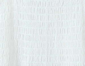 Detail of white embroidered smocking fabric with elastic shirring texture on the summer set
