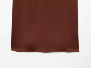 Detail shot of deep brown satin dress hem showing smooth silk texture and fine stitching