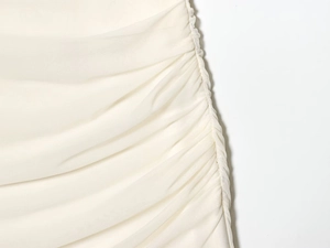 Detail view of cream ruched mesh fabric and stitching on a slim sleeveless dress
