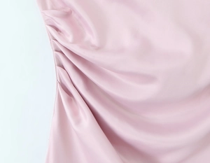 Detailed close-up of pink satin dress side featuring elegant ruched draping and silky texture