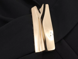 Vue détaillée d'une boucle métallique dorée ondulée sur un tissu en maille noire