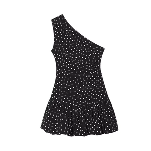 Detailed close-up of one-shoulder polka dot dress with pleated ruffle hem and wrap chest design