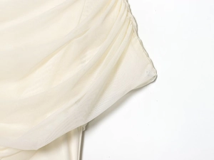 Detailed view of the elegant cream pleated mesh fabric and ruched texture on the dress