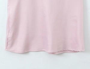 Detailed close-up of pink satin dress hem featuring white topstitched seam edges
