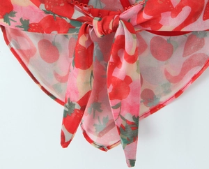 Detail of red strawberry print on light fabric with center tie knot and scalloped hem