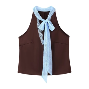 Detail of dark brown halter top featuring a delicate light blue lace bow on the neckline