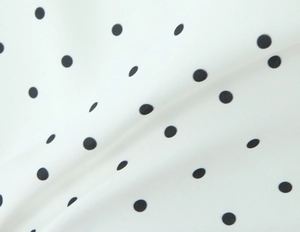 Detail shot of smooth white fabric with black polka dot pattern and soft texture