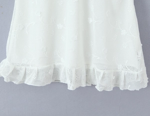 Close-up of white lace dress detailing with floral hollow patterns and ruffle hemline