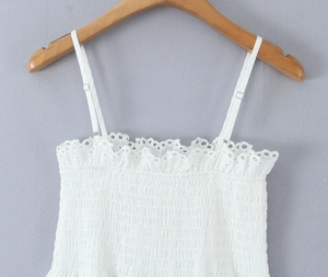 Close-up of white smocked camisole featuring eyelet lace trim and adjustable straps