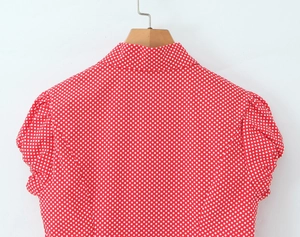Detail of red short-sleeve shirt with white polka dots featuring a classic lapel collar