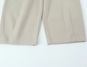 Détail macro du pantalon beige clair montrant la couture de l'ourlet et le pli central
