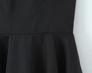 Détail de la taille ajustée et de la jupe plissée sur une robe d'été tissée noire
