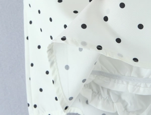 Macro view of white polka dot fabric with detailed stitching and elastic ruching detail
