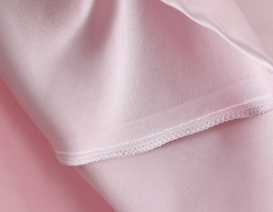 Detail of pink satin fabric showing smooth texture and high-quality double stitching