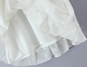 Detail view of intricate white floral lace hem and silky inner lining on a summer dress