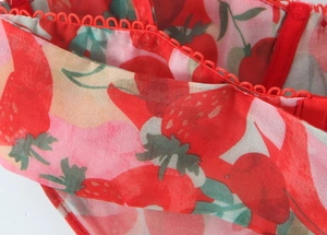 Detail of red strawberry print on sheer fabric with delicate lace trim and thin straps