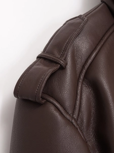 Macro shot of dark brown leather jacket shoulder with epaulet detail and texture