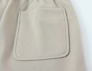Détail de la poche plaquée et du tissu en laine texturée couleur avoine d'un ensemble femme