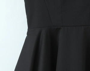 Détail de la taille d'une robe noire cintrée avec coutures et ourlet évasé