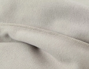 Détail macro du tissu en maille douce haute densité avec une couture surjet précise