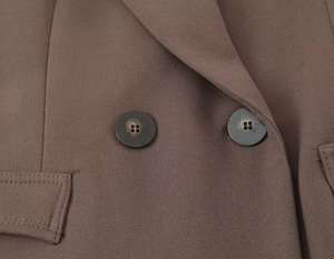 Detailed close-up of brown blazer buttons and woven fabric texture with pocket flap