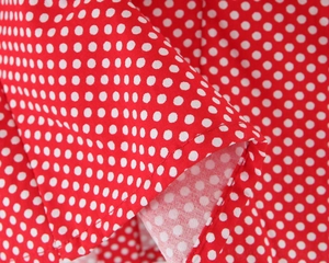 Detail view of red fabric with white polka dots showing neat stitching and folded hem