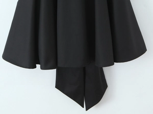Détail de l'ourlet d'une robe noire élégante montrant des plis et un nœud décoratif