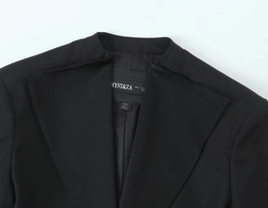 Détail du col d'un blazer noir avec étiquette de marque et informations de taille