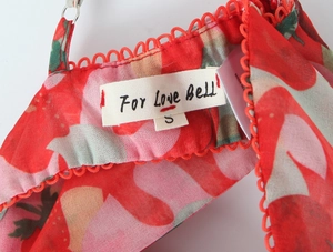 Detail of red floral camisole neckline with delicate lace trim and brand label