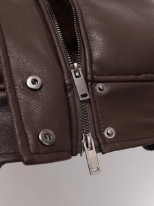 Macro detail of dark brown leather jacket featuring metal zippers and snap buttons