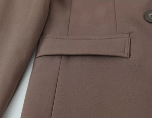 Detail of coffee brown blazer flap pocket showing fine stitching and twill fabric texture