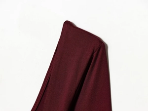 Detail view of burgundy knitted fabric with fine stitching and vertical rib texture