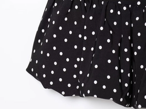 Detailed view of black and white polka dot fabric with elegant pleated textures
