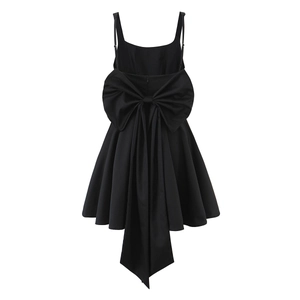Détail du grand nœud au dos d'une mini robe noire ajustée avec des rubans tombants
