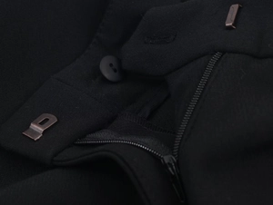 Détail d'un pantalon de costume noir avec fermeture éclair en métal et tissu texturé