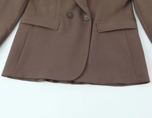 Detail of brown double-breasted blazer showing fabric texture and flap pockets