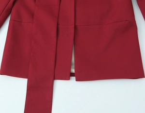 Detail of deep red structured blazer hem and wide matching fabric belt stitching