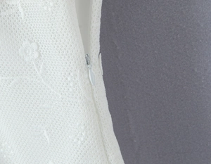 Detail of delicate white floral lace fabric with a premium invisible zipper closure